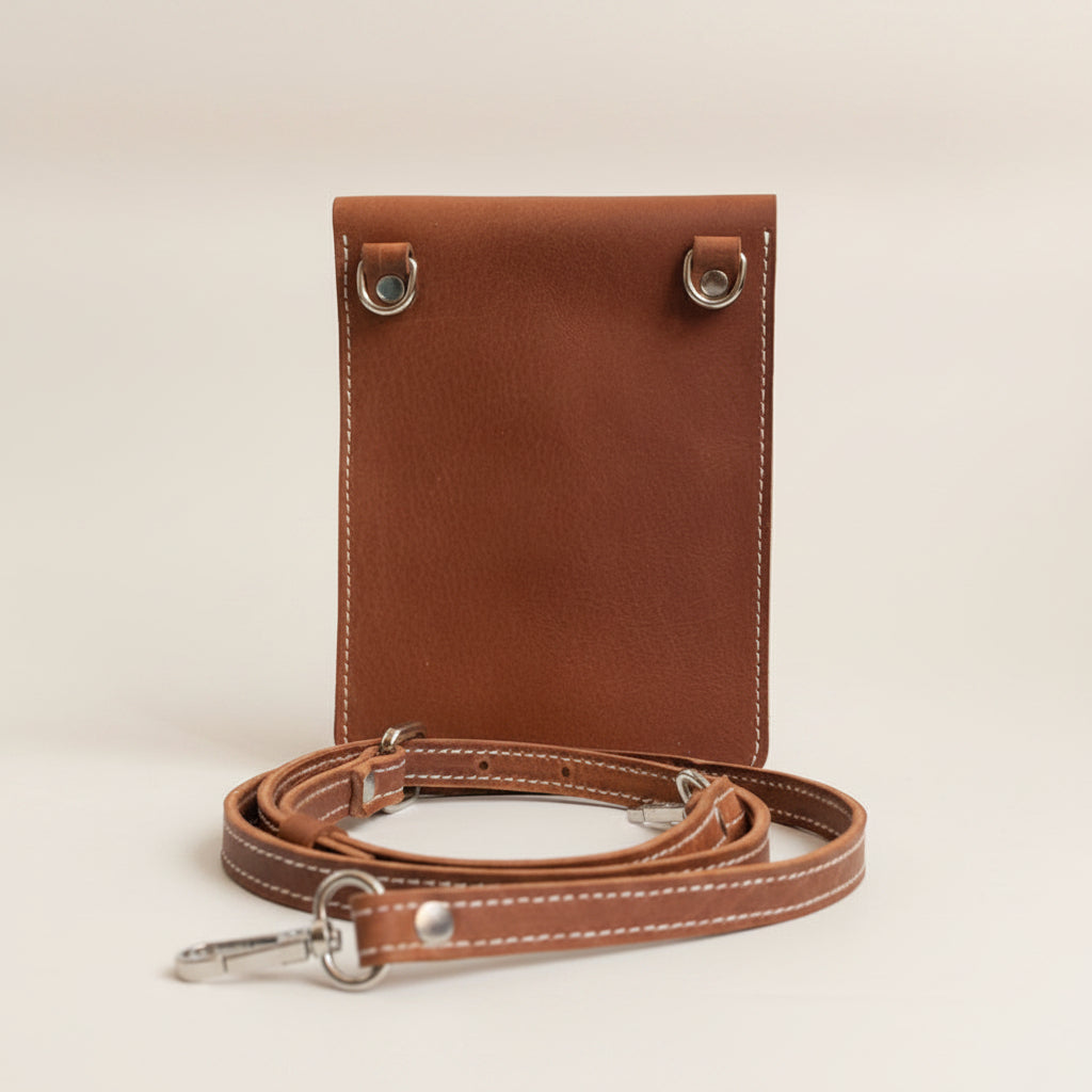Brown leather crossbody bag with strap on a light gray background