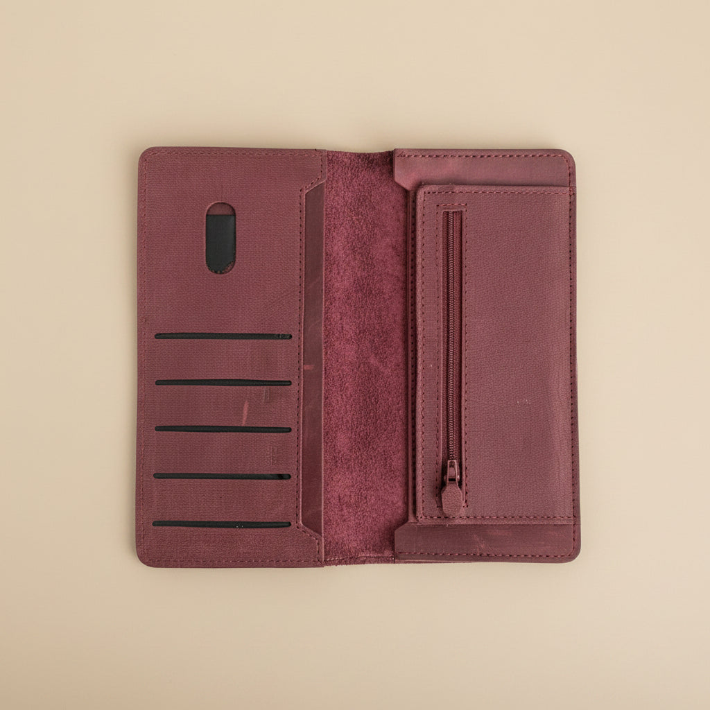 Maroon phone wallet case with card slots and a zipper on a white background