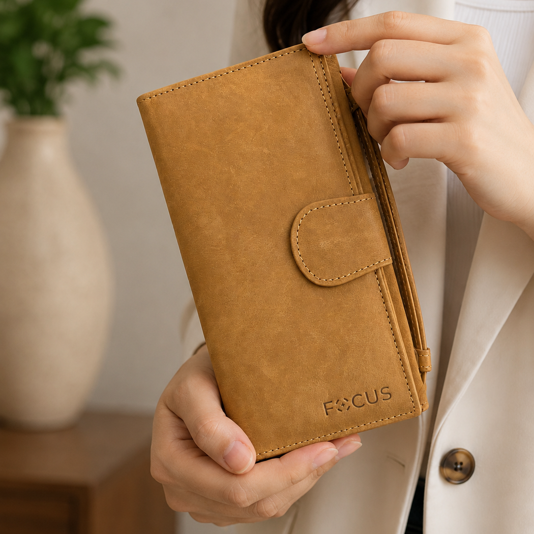Person holding a brown leather wallet with 'FOCUS' branding against a neutral background