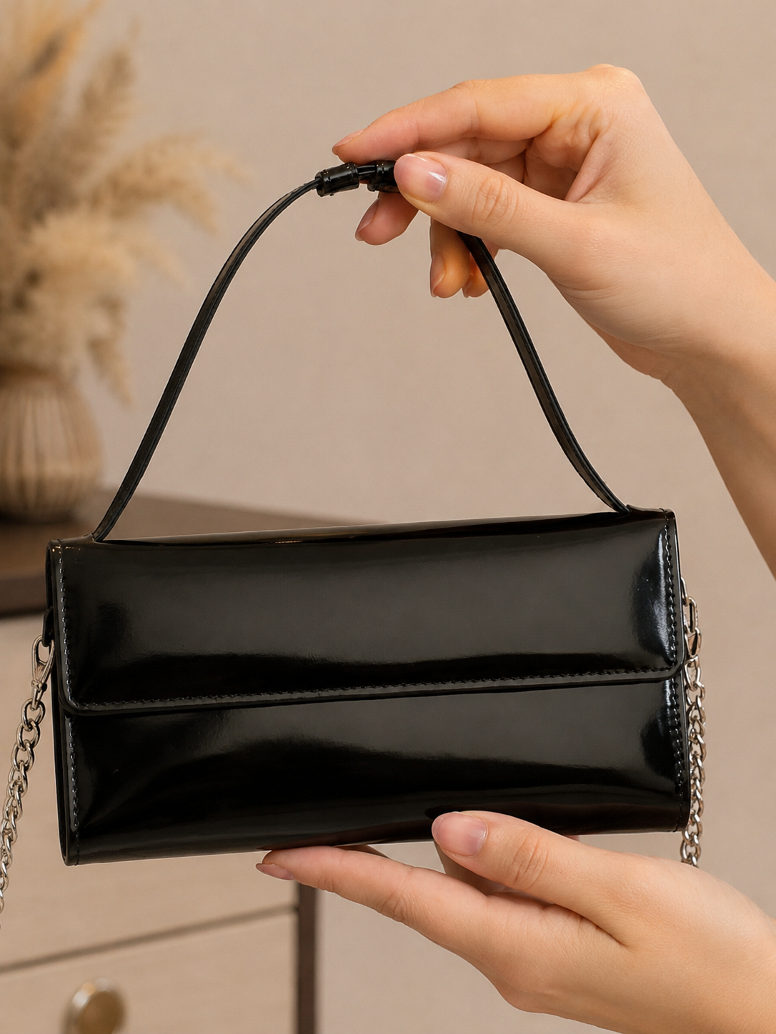 Black handbag held by a person with a neutral background