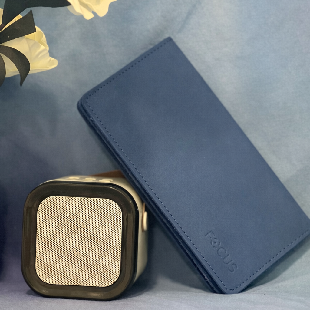Blue wallet and square speaker on a textured surface with flowers in the corner