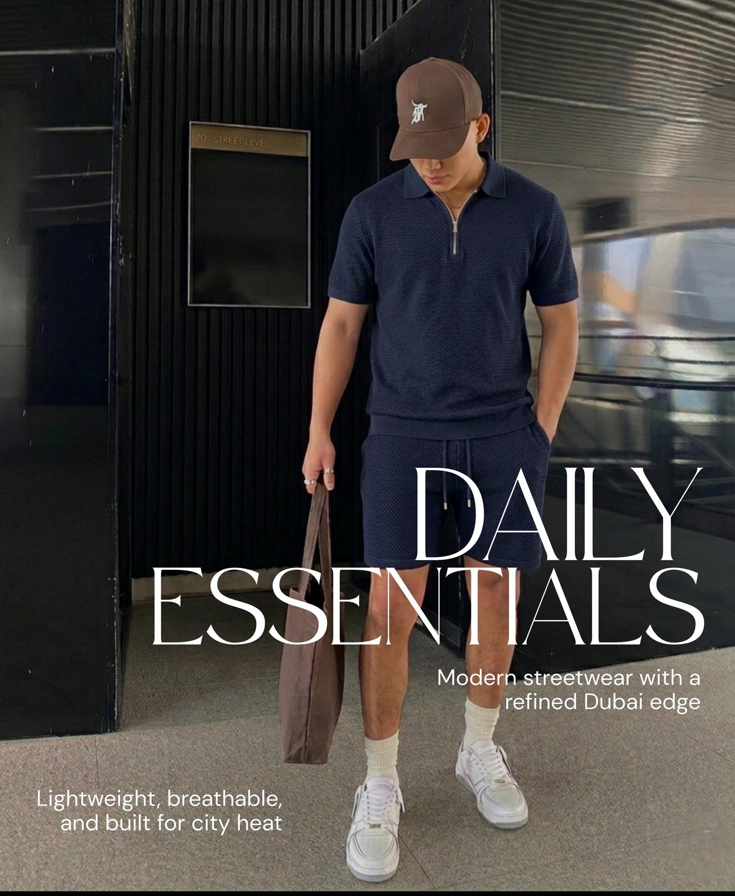 Man in navy polo shirt and shorts holding a bag, with 'Daily Essentials' branding.